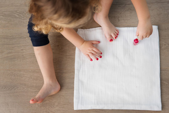 High angle view of little girl applying nail polish
