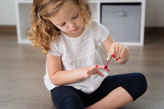 Close up of little girl applying nail polish to fingernails