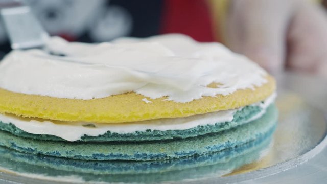 Scooping whipped cream on to colored cake layers