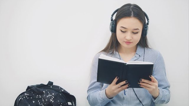 Inspired young asian girl sitting on the floor, doing homework, writing, listening to music, dancing.
