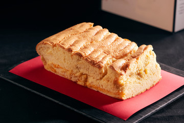  Tet holiday concept. Custard cake on a black stone plate with red paper
