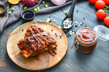 Plate with fried meat and barbecue sauce on dark table