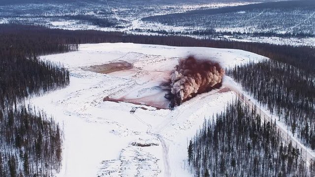 blow up of a mineral deposits. mined territory in field in forest in winter. coal mining. extractive industry for coal, top view aerial drone shot of explosion.