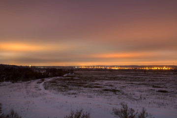 Winter landscape. View of the big city lights from the forest park in the late evening