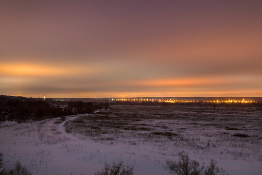 Winter landscape. View of the big city lights from the forest park in the late evening © Konstantin