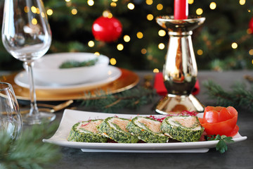 Spinach roulade with salmon and cottage cheese. Christmas dishes, festive table setting. Horizontal composition.