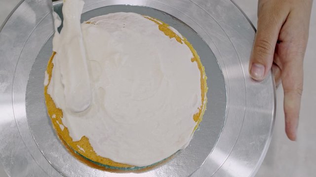 Icing a cake with whipped cream and a spatula