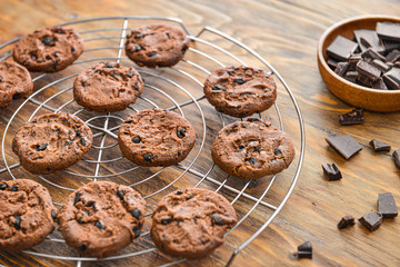 Cooling rack with tasty chocolate chip cookies on wooden table