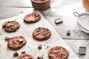 Tasty chocolate chip cookies with flour on wooden background