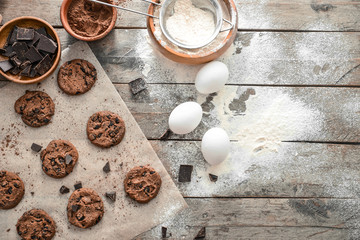 Obraz na płótnie Canvas Tasty chocolate chip cookies with flour and eggs on wooden background