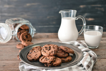 Tasty chocolate chip cookies with milk on wooden table