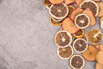 Fototapeta na wymiar Slices of dry lemon, oranges and apples on a grey structured background
