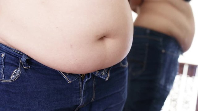 overweight woman checks the fat on her stomach. obesity problem