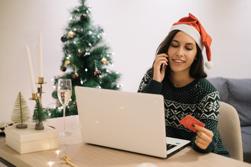 Girl buying gifts by phone in front of the laptop