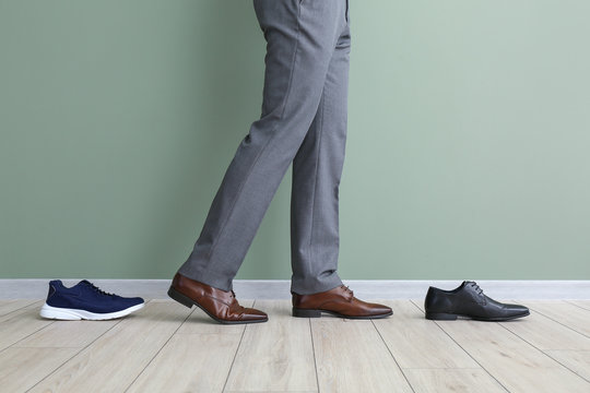 Young man with different stylish shoes near color wall