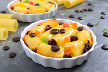Sweet cannelloni, baked in ceramic forms. Dessert of canelloni, cottage cheese, candied fruit, dried cherries, chocolate drops. Tasty breakfast.