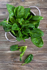 Fresh spinach leaves in a bowl on a wooden table. Useful, tasty, low-calorie greens. Young spinach...