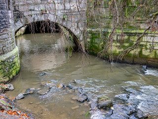  Fast flowing rocky river and ancient stone bridge in the Dutch town of Maastricht