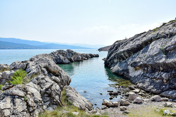 Fototapeta na wymiar Rocks on the seashore, a small bay with clear water and stones, the island of Krk Croatia, in the summer afternoon, clear weather.