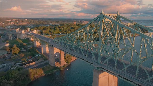 AERIAL: Flying over the Pont Jacques-Cartier bridge, Saint Lawrence River and Montreal city skyline at sunset, Quebec, Canada