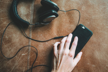 Top view of hand holding smartphone next to headphones