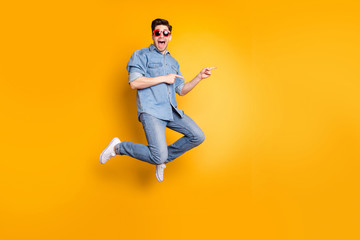 Fototapeta na wymiar Full length body size view of nice attractive funky overjoyed cheerful cheery guy jumping pointing aside advert tips isolated over bright vivid shine vibrant yellow color background