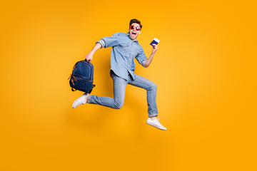 Fototapeta na wymiar Full length body size turned photo of screaming man running jumping towards airport in white shoes and satchel in hands isolated vivid yellow color background