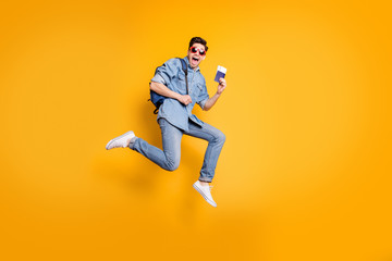 Naklejka na ściany i meble Side profile full length body size photo of screaming crazy man holding passport ticket with hands in white footwear near empty space isolated vivid yellow color background