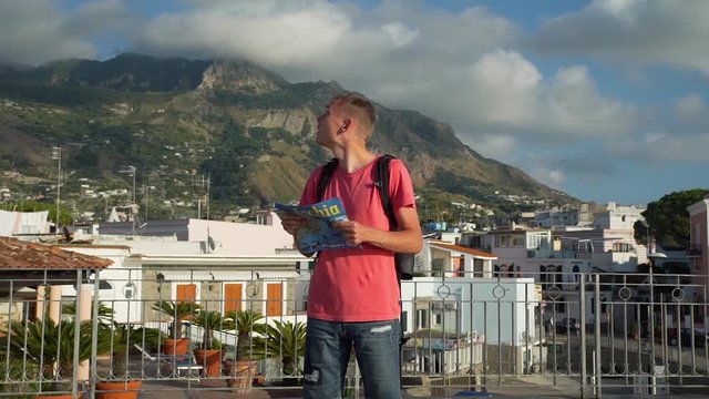 Young Man Tourist Exploring Forio Town on Ischia Island in Italy at Sunset. He is Holding Tourist Map in his Hands and Trying to Determine his Location.