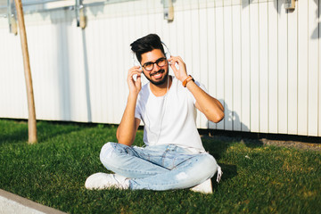 Young indian Student sitting on the grass. Urban style.