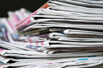 Newspapers folded and stacked on the table dark background. Closeup newspaper and selective focus image.