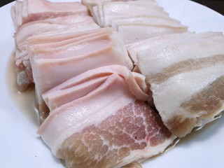 Raw meat, Top view of pork belly on white plate as a background in restaurant, fresh meat for grill or cooking, Kurobuta Bara is japanese traditional