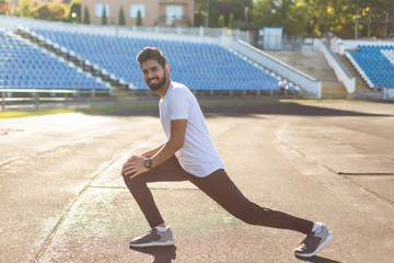 Fototapeta premium Young indian man doing stretching exercise on running track