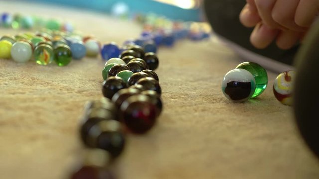 Girl pulling a pile of marbles closer to a line of color sorted marbles.