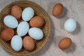 several fresh chicken eggs in a straw basket on a wooden background. Healthy eating concept.