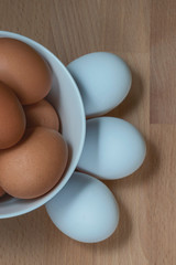 several fresh chicken eggs in a ceramic cup on a wooden background. Healthy eating concept