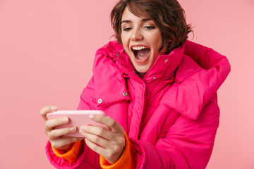 Portrait of young excited woman playing video game on cellphone