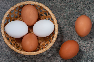 several fresh chicken eggs in a straw basket on a wooden background. Healthy eating concept.