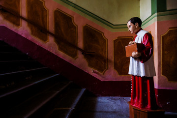 Old statue of acolyte or altar boy with collecting box for gifts in church