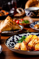 The concept of Uzbek cuisine. Different oriental dishes on the table in national Uzbek plates. Rustic fried potatoes. background image. copy space