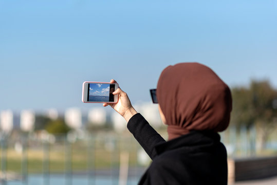 Muslim young woman takes photos by the sea