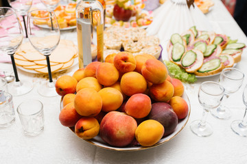 Fresh fruit peaches, apricots and plums on a plate on the holiday table