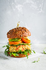 Vegan burger with vegetable cutlet, sweet potato, avocado, cucumber and arugula, copy space. Healthy plant based food concept.