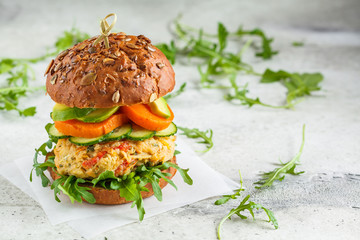 Vegan burger with vegetable cutlet, sweet potato, avocado, cucumber and arugula, copy space. Healthy plant based food concept.