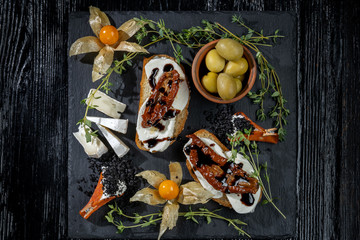 Fototapeta na wymiar Snacks are laid out on black slate, physalis, salami, cheese and sun-dried tomatoes-2.
