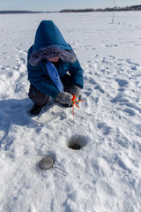 Fototapeta na wymiar Boy fishing with a fishing rod on the ice in winter