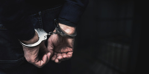 Fototapeta handcuffed arrested man behind prison bars. copy space obraz
