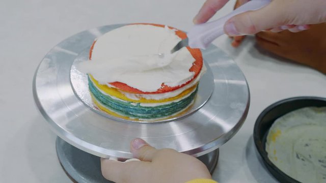 Icing a cake with whipped cream and a spatula