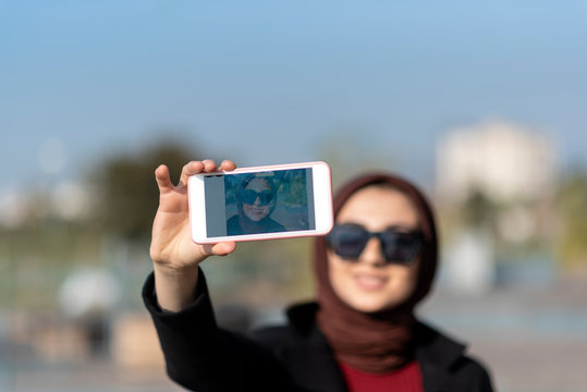 muslim young woman is taking self photo in public park