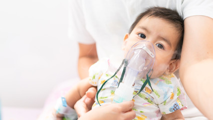 Close up of asian little baby boy is treated respiratory problem with vapor nebulizer to relief cough symptom in the hospital room , concept of pediatric patient care for sick in the hospital.